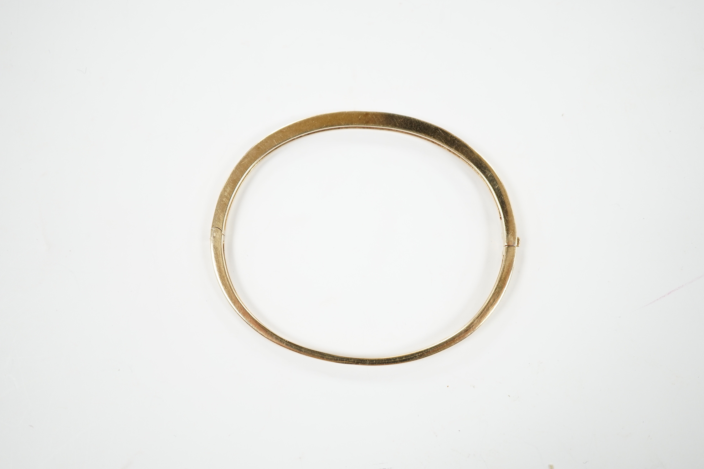 A yellow metal, ruby and diamond chip channel set hinged bangle, interior diameter 57mm, gross weight 10.8 grams.